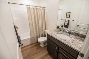 Bathroom with wood finished floors, vanity, and shower / tub combo with curtain