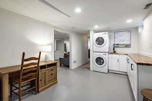 Laundry room with estacked washer and dryer, cabinet space, and recessed lighting