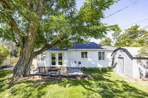 Rear view of house with a storage unit, a patio area, french doors, and brick siding