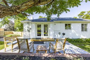 Rear view of property featuring a chimney, french doors, a patio, and brick siding