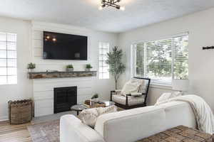 Living room featuring a glass covered fireplace, light wood-type flooring, and a chandelier