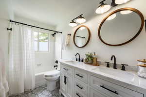 Bathroom with double vanity, shower / tub combo with curtain, and tile patterned floors