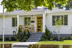View of exterior entry with brick siding and a shingled roof