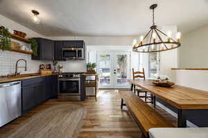 Kitchen with french doors, stainless steel appliances, tasteful backsplash, light wood finished floors, and open shelves