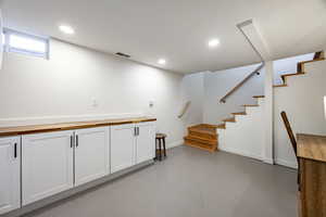 Bar area featuring concrete floors, recessed lighting, and stairway