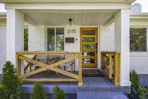 View of exterior entry with brick siding and a porch