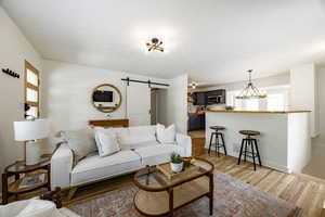 Living area featuring a barn door, a chandelier, and light wood-type flooring