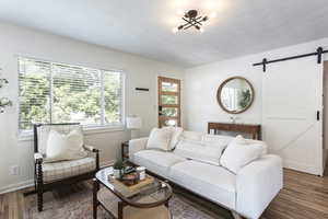 Living area featuring a barn door and wood finished floors