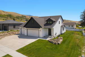 Modern farmhouse with a mountain view, concrete driveway, a front lawn, and a garage