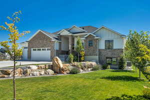 Craftsman inspired home featuring board and batten siding, a front yard, driveway, and brick siding