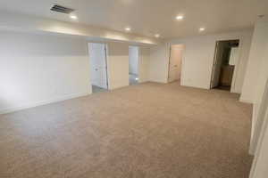 Living room with recessed lighting, light colored carpet, and connected bathroom