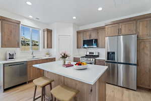 Kitchen featuring appliances with stainless steel finishes, recessed lighting, light wood-type flooring, a center island, and light countertops