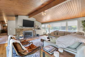 Living room with light wood-style flooring, a glass covered fireplace, and wooden ceiling
