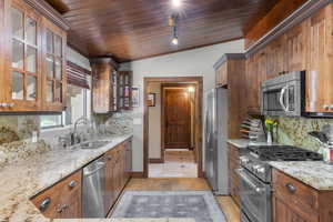 Kitchen featuring backsplash, appliances with stainless steel finishes, light stone counters, lofted ceiling, and wooden ceiling