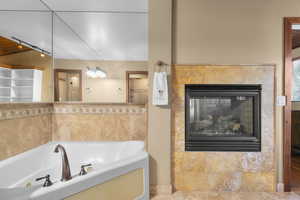 Full bathroom featuring a jetted tub and a tile fireplace