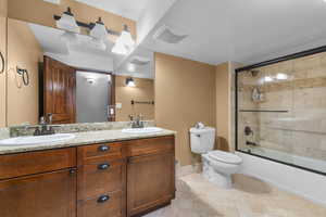 Full bath featuring double vanity, enclosed tub / shower combo, and tile patterned flooring