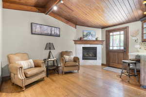Sitting room featuring wooden ceiling, track lighting, a premium fireplace, and light wood-type flooring