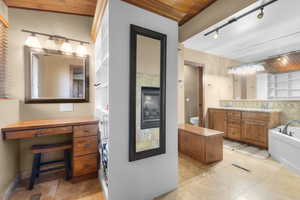 Kitchen with tasteful backsplash, light tile patterned floors, rail lighting, brown cabinets, and wooden ceiling