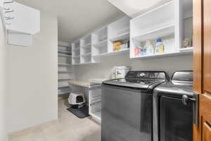 Laundry room featuring washing machine and clothes dryer and light tile patterned floors