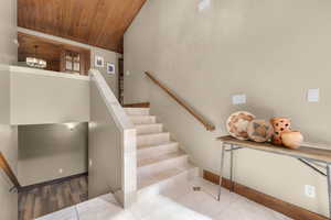 Staircase with tile patterned flooring and wooden ceiling