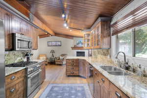Kitchen featuring backsplash, stainless steel appliances, track lighting, open floor plan, and wood ceiling