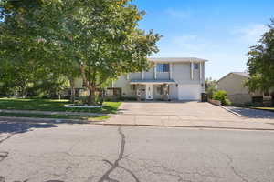 View of front of house featuring concrete driveway, an attached garage, and a front lawn