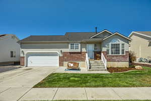 Single story home with brick siding, driveway, an attached garage, and a front lawn