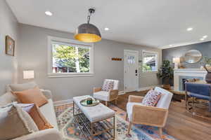 Living room featuring wood finished floors, a fireplace with flush hearth, and recessed lighting