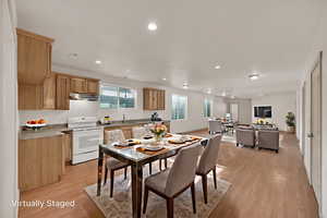 Basement kitchen/dining/family room with light wood-style flooring, natural light, and recessed lighting