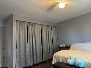 Bedroom featuring a textured ceiling, dark wood-type flooring, and ceiling fan