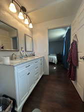 Full bathroom with wood finished floors, double vanity, connected bathroom, and a textured wall