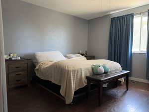 Bedroom with dark wood finished floors and baseboards