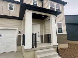 View of exterior entry with a garage and a porch