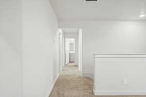 Hall with light colored carpet and recessed lighting