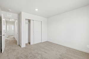 Unfurnished bedroom with light colored carpet, a closet, and recessed lighting