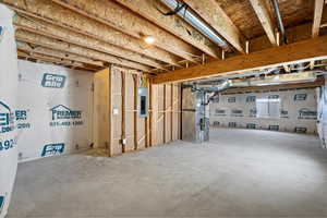 Below grade area featuring heating unit and electric panel