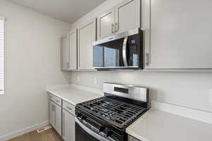 Kitchen featuring appliances with stainless steel finishes, light wood finished floors, and gray cabinetry