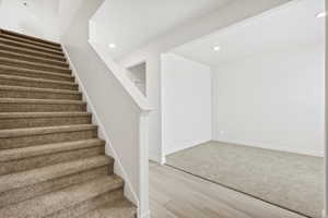Staircase with recessed lighting and wood finished floors