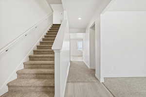 Stairs with wood finished floors, recessed lighting, and carpet flooring