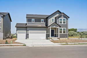 View of front of home with board and batten siding, roof with shingles, concrete driveway, and a garage