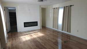 Unfurnished living room with a large fireplace and wood finished floors