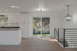 Kitchen featuring dark countertops, light wood-style flooring, white cabinetry, pendant lighting, and a chandelier