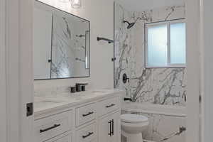 Bathroom featuring double vanity and a combined bath / shower with marble appearance