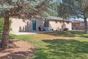 Rear view of house featuring a yard, brick siding, and a patio