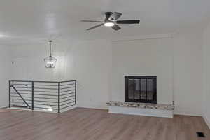 Unfurnished living room with wood finished floors, a fireplace, and ceiling fan