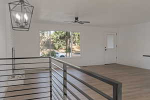Staircase with wood finished floors, ceiling fan, and a chandelier