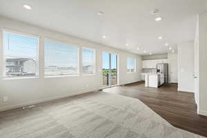 Unfurnished living room featuring recessed lighting and dark wood-style flooring