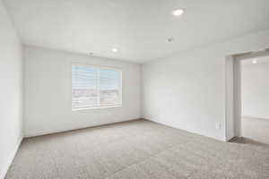 Empty room with light colored carpet, recessed lighting, and a textured ceiling