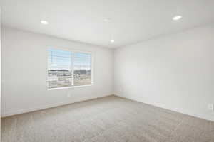 Empty room with light carpet and recessed lighting