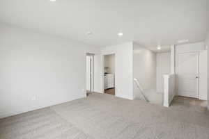 Empty room with recessed lighting, light colored carpet, and washer and dryer